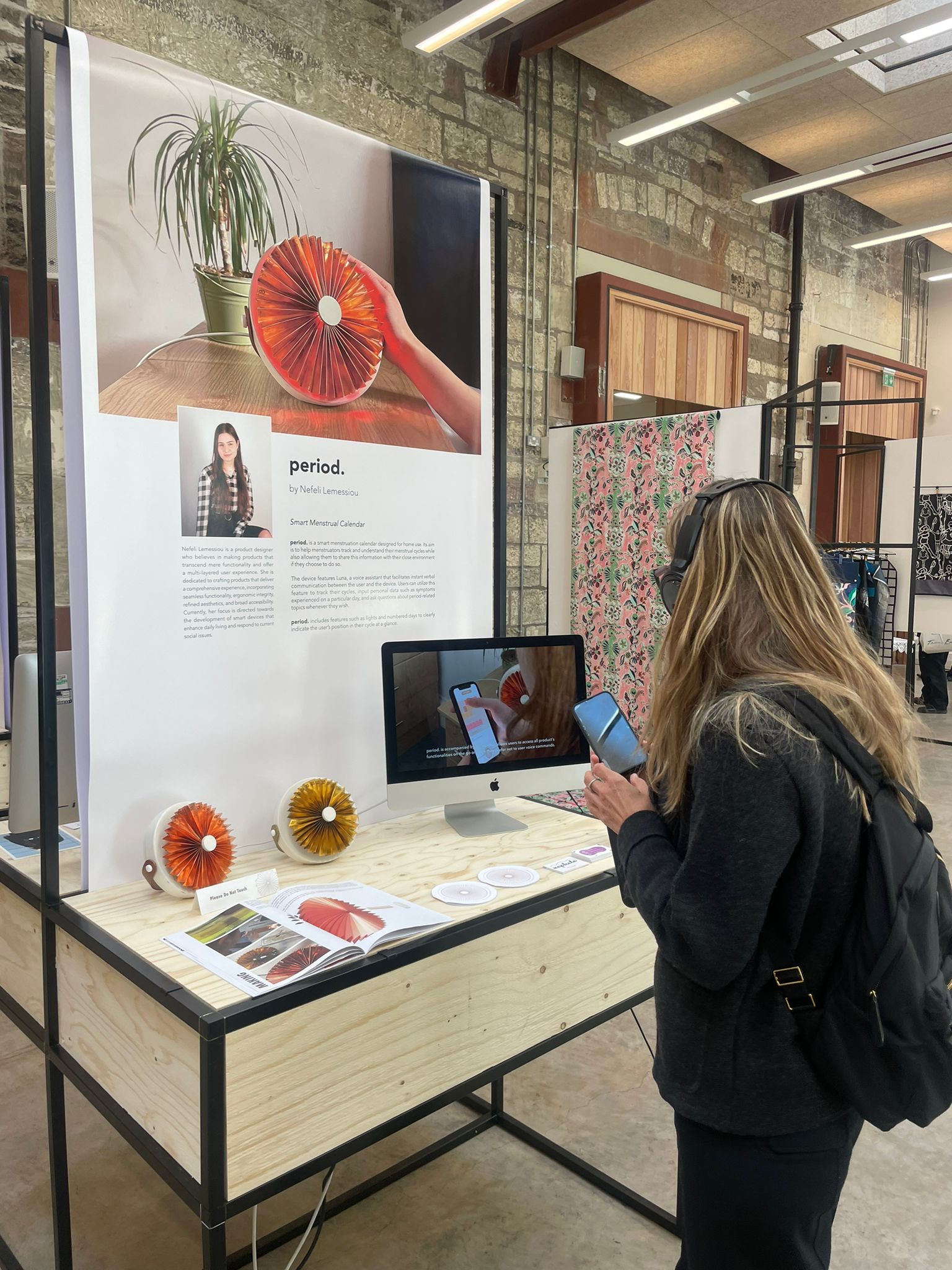 A visitor with headphones watching the period. demo video and trying the app at the stand