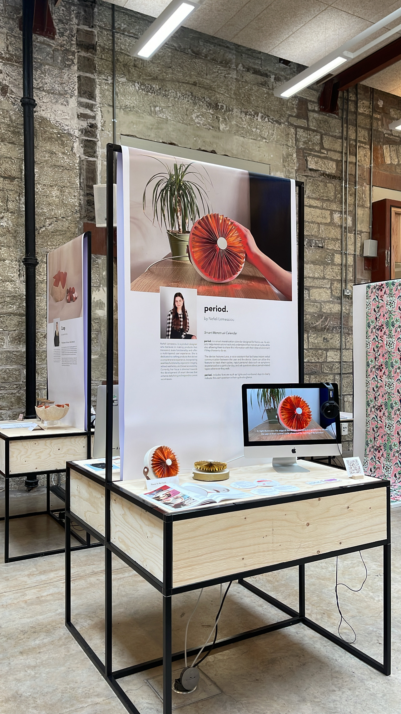 Angled view of the period. plinth and poster wall within the wider Product Design exhibition space