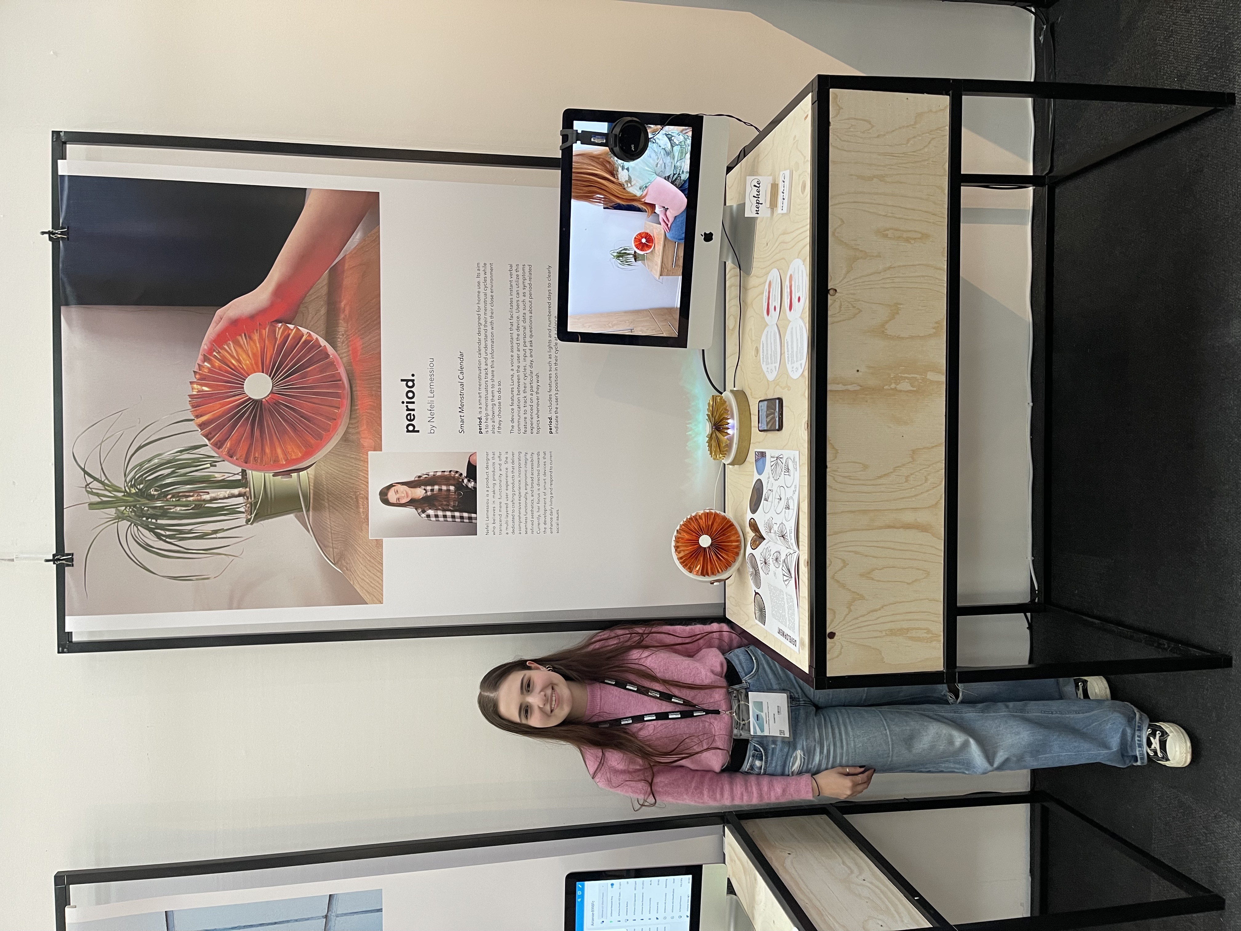 Nefeli at her period. stand at New Designers, with the device, supporting materials, a demo video and project poster behind