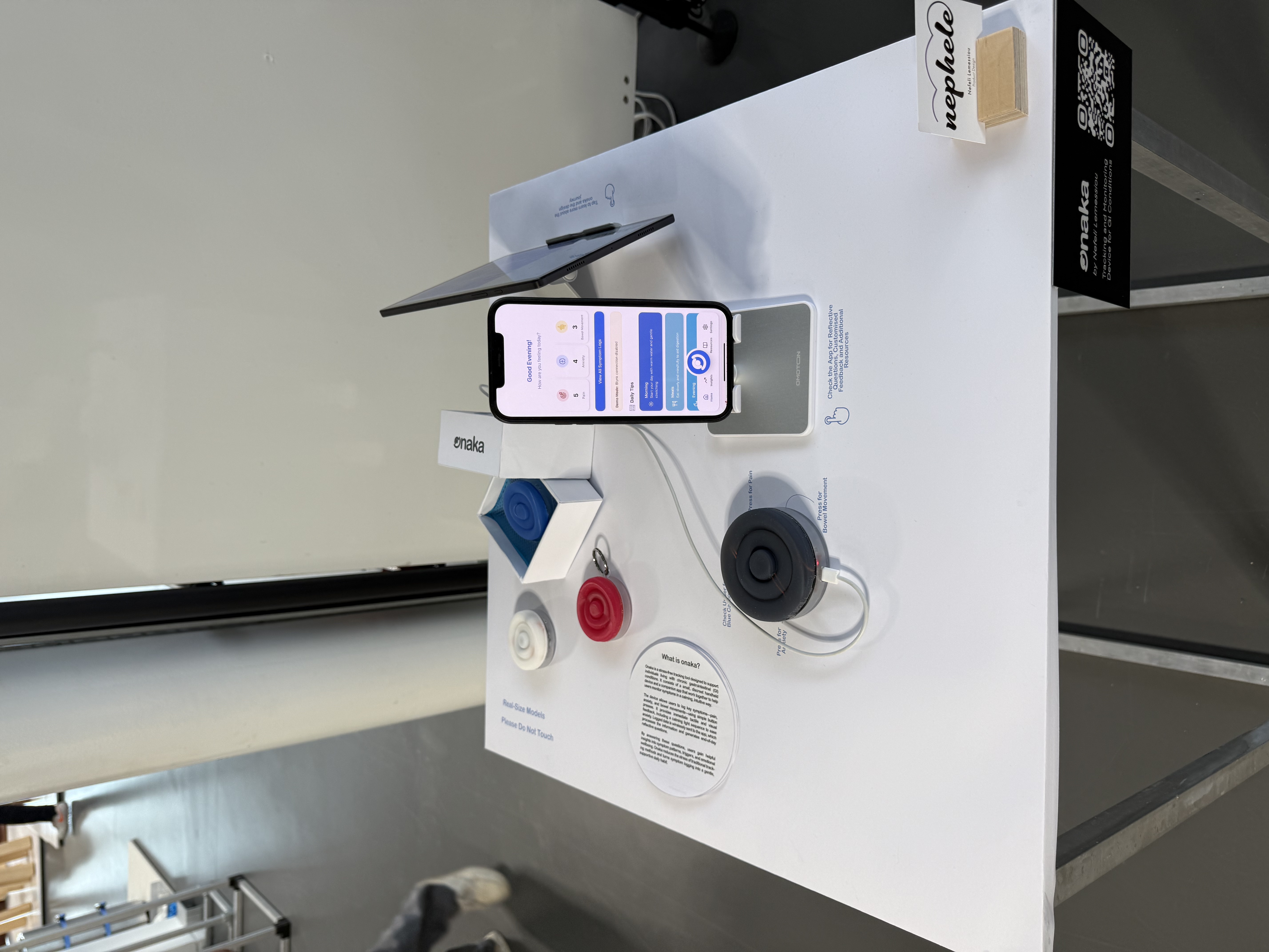 The Onaka stand at the RCA Graduation Show: real-size silicone device models and the companion app running on a phone, on a white plinth