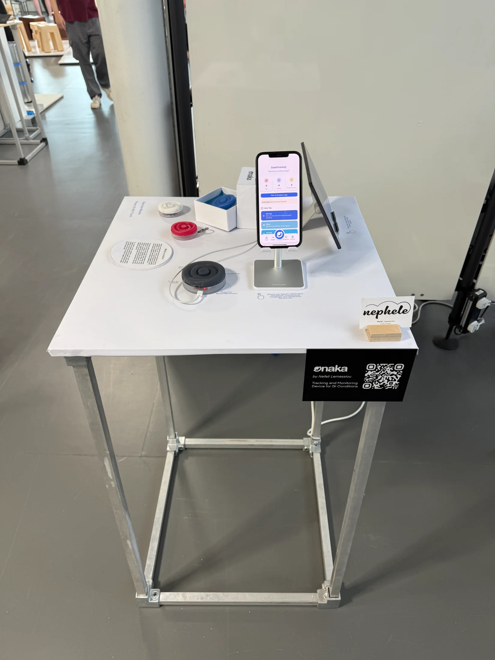 Close detail of the Onaka display: silicone models, packaging, app on the stand, and the nephele business cards