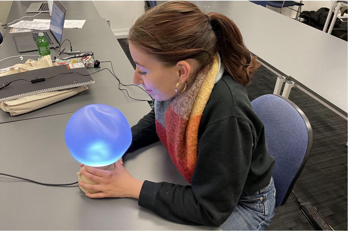 A student trying the Ilia lamp during a quick studio session, hands on the wooden base