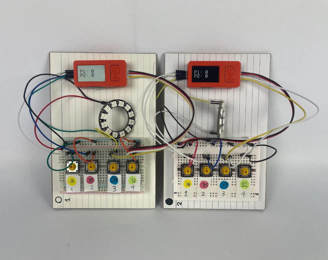 The Milo electronics laid out: two M5 Stick C Plus boards, NeoPixel ring, four push buttons, a speaker, and a side button, all wired together on a breadboard during testing