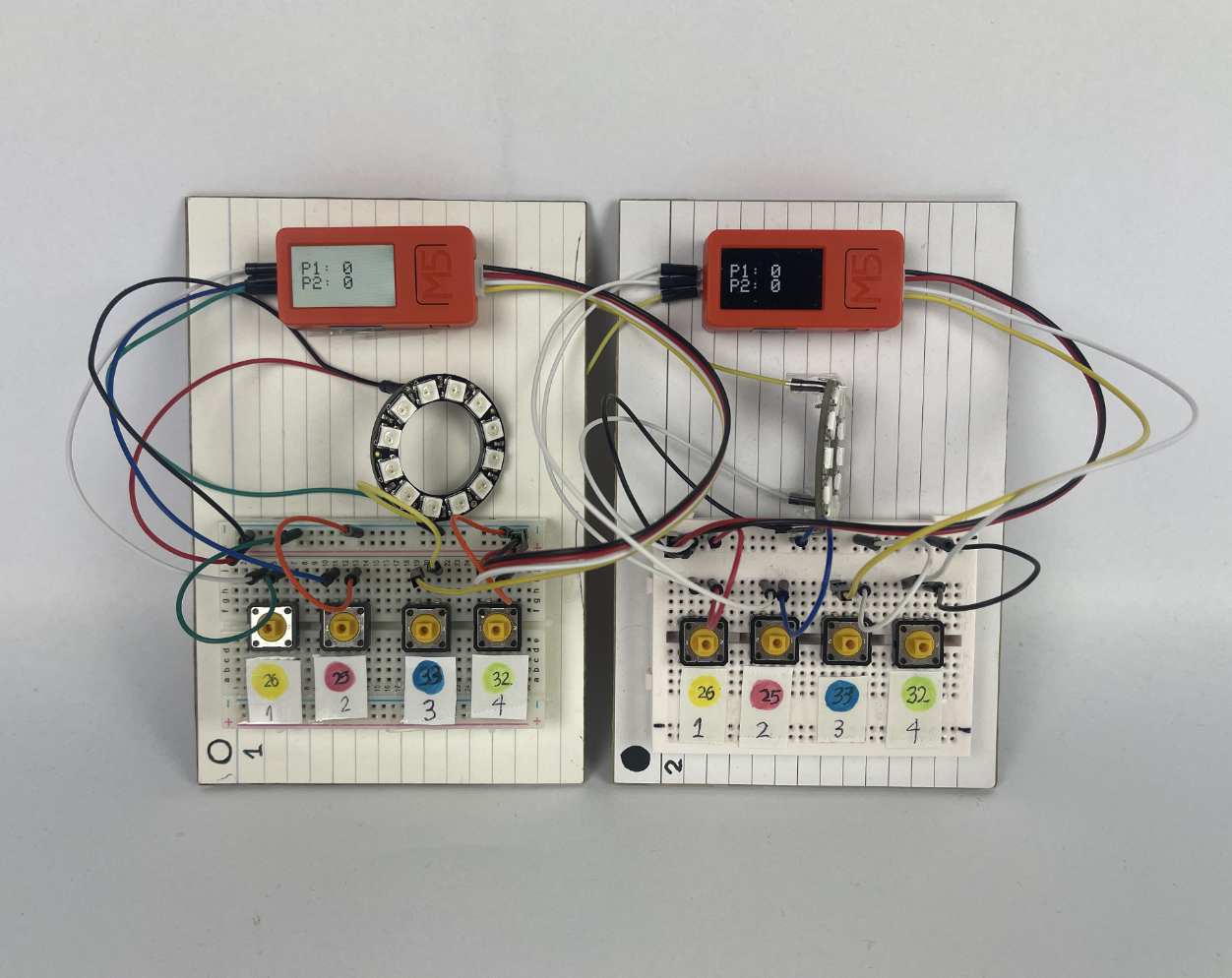 The Milo electronics laid out: two M5 Stick C Plus boards, NeoPixel ring, four push buttons, a speaker, and a side button, all wired together on a breadboard during testing