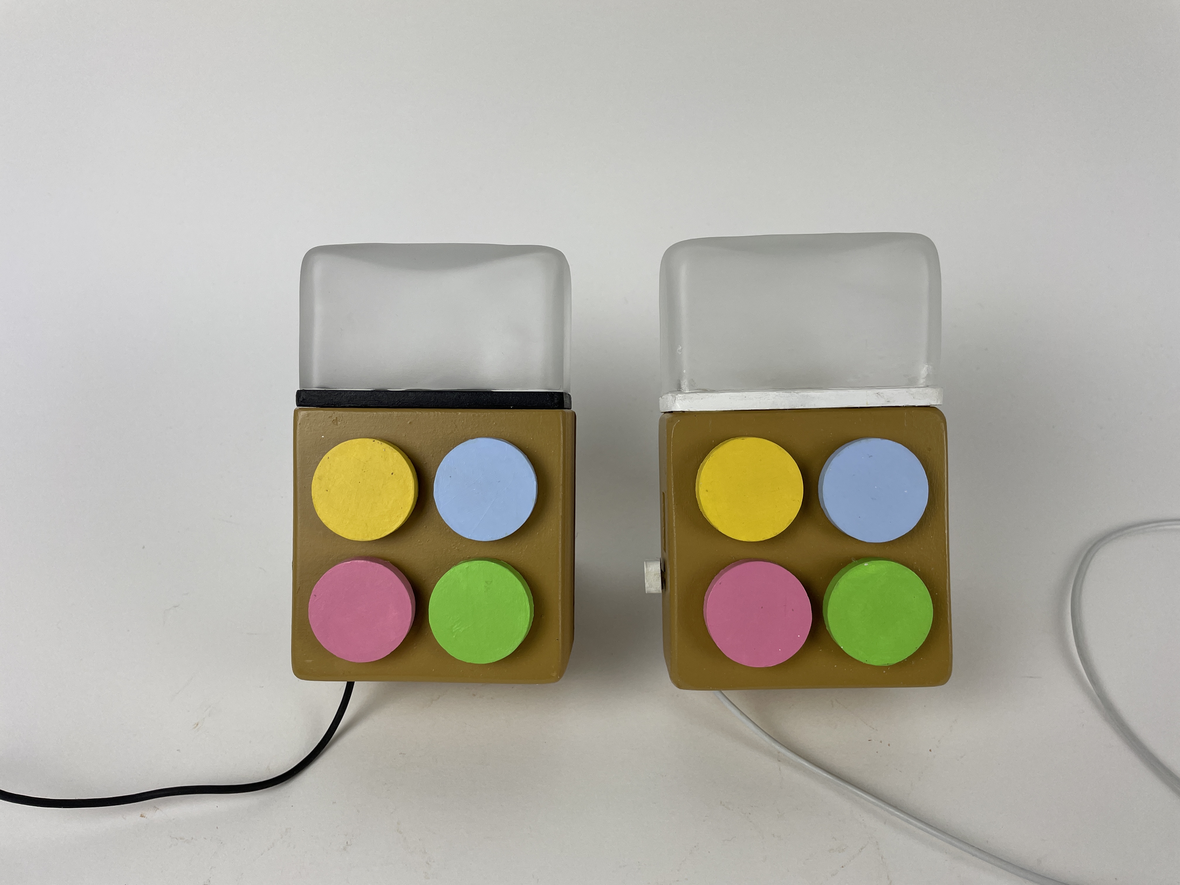 The resolved Milo pair photographed together, white and black diffuser caps lit, four pastel buttons visible on each