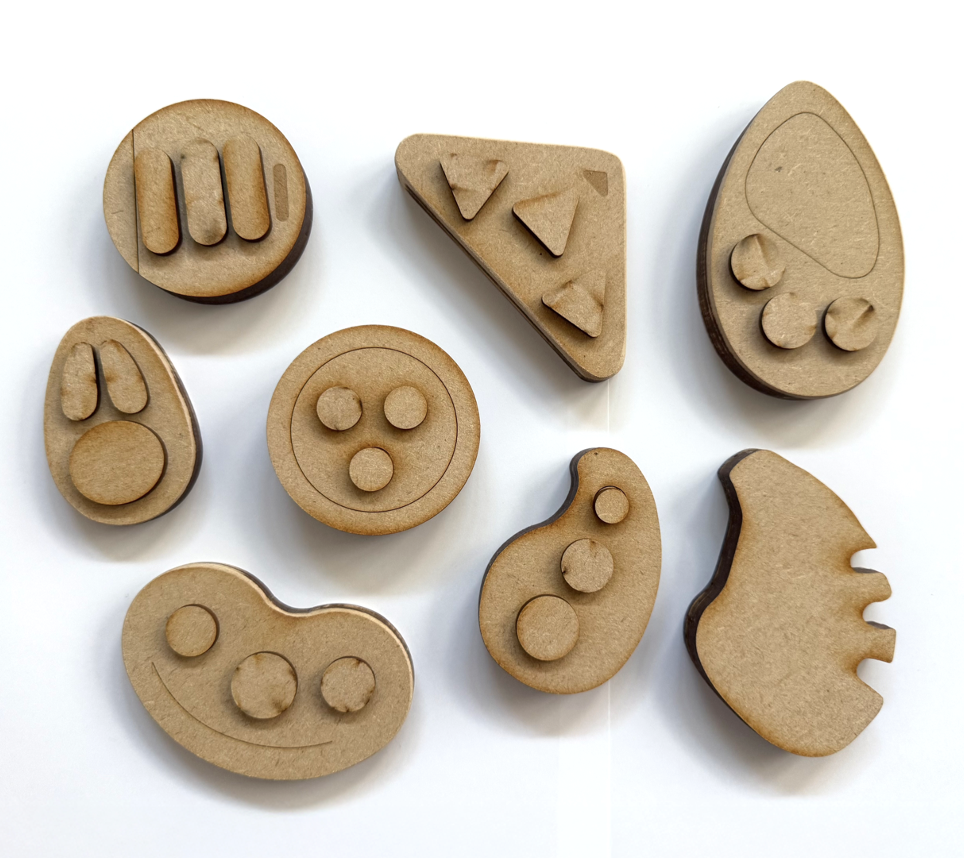 MDF prototypes laid out, each a different form being held and pressed