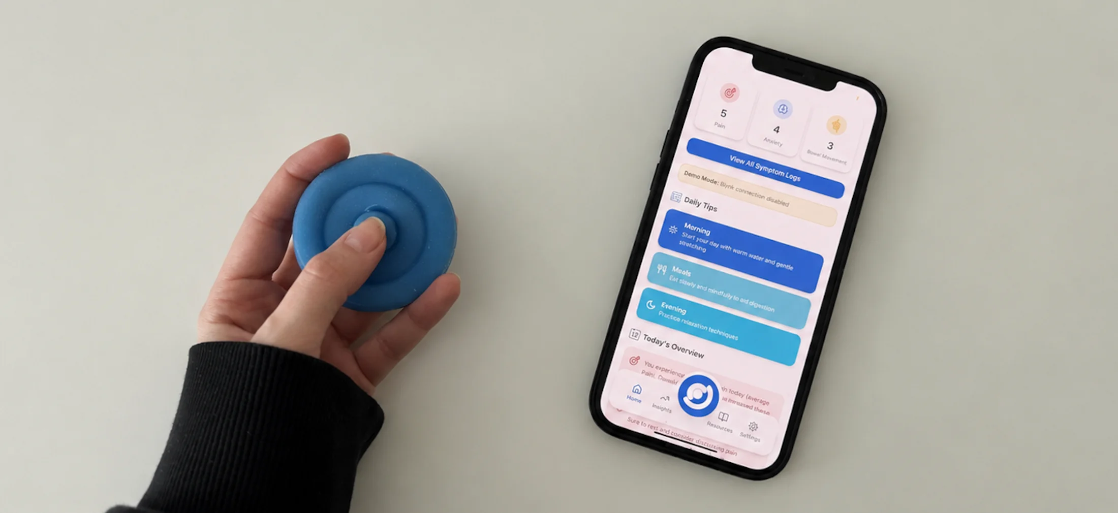 A hand pressing the blue Onaka device beside a phone showing the onaka companion app dashboard with symptom counts and daily tips