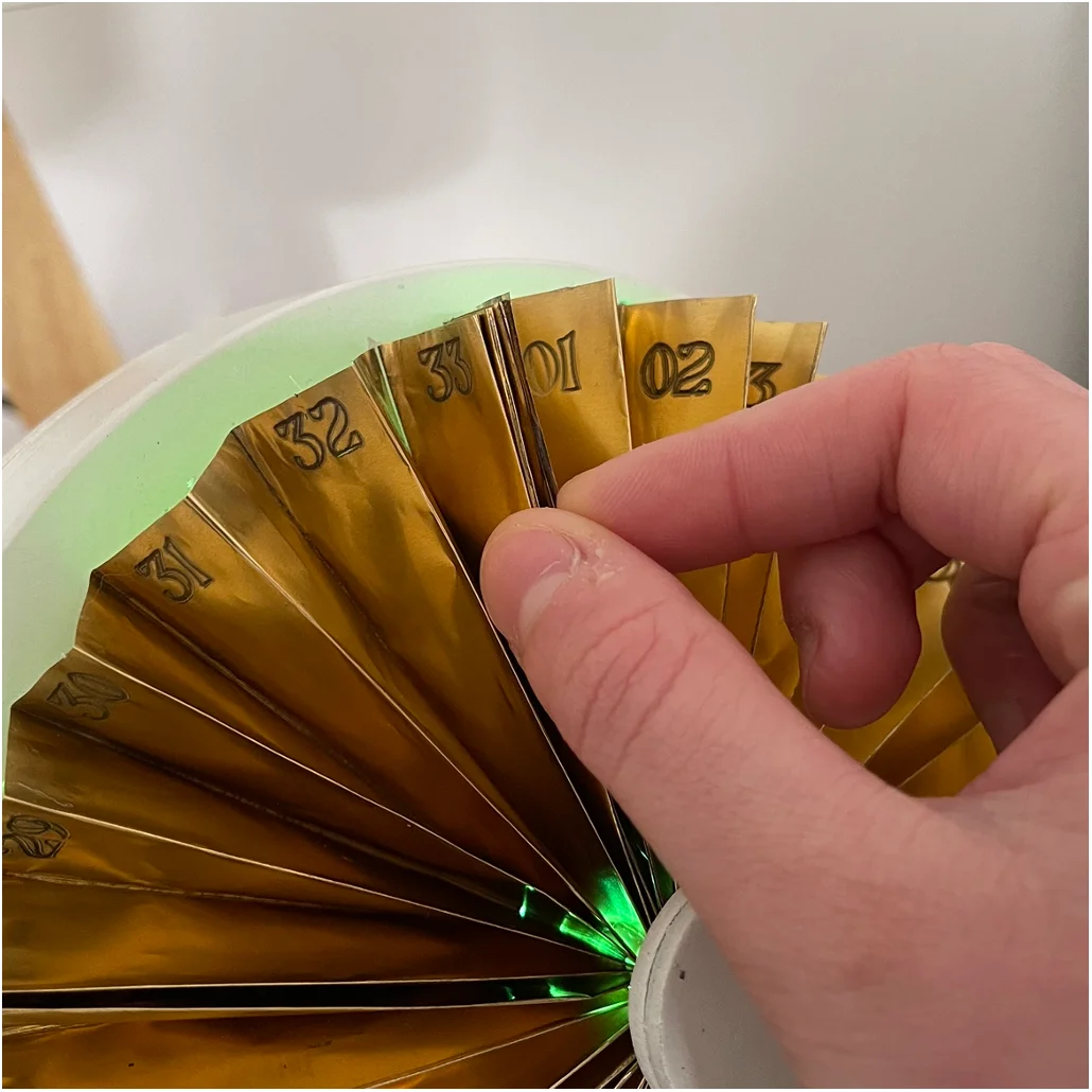 Close-up of the copper fan showing day numbers and rotating pointer