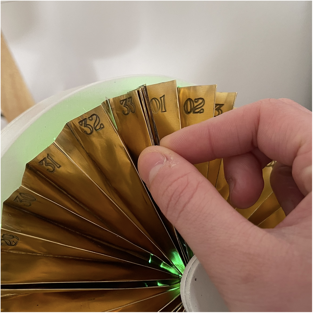 Close-up of the copper fan showing day numbers and rotating pointer