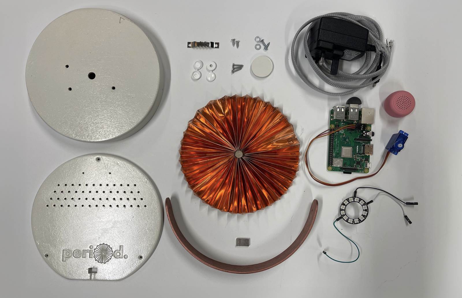 Flat lay of every component used to build the period. device, base, lid, copper fan, handle, electronics, screws, cable