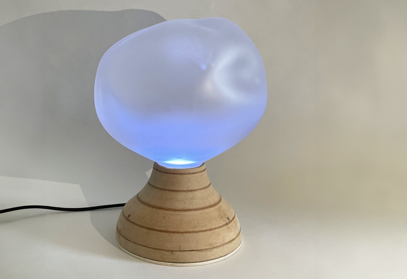 The Ilia breathing lamp: blue glowing organic glass diffuser on a turned wooden base