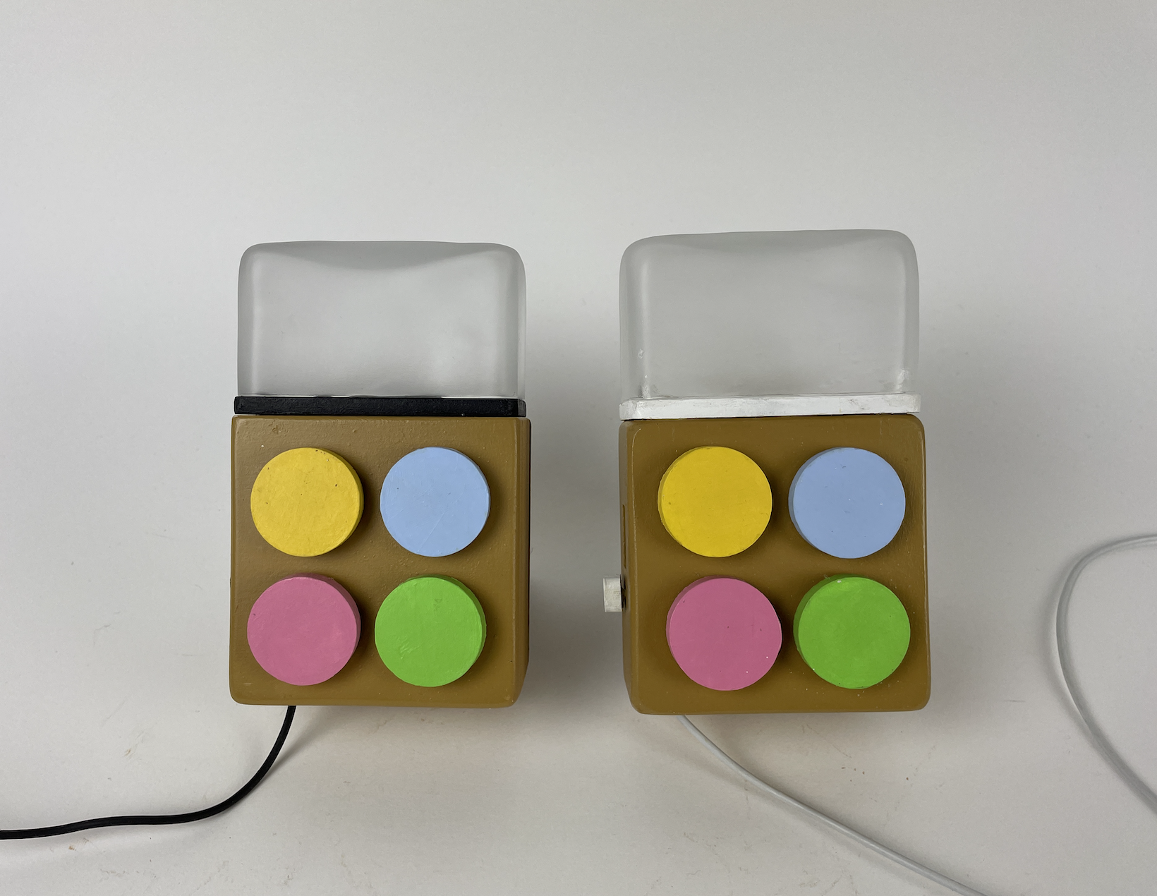 The Milo pair photographed front-on: two small wooden boxes with frosted glass tops and four pastel buttons each