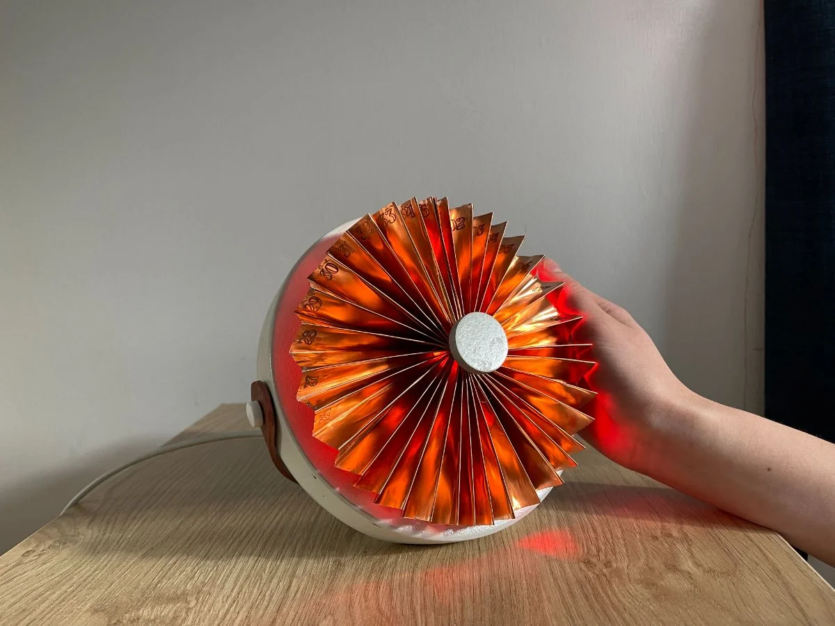 The period. device on a wooden surface, copper fan-shaped calendar glowing red
