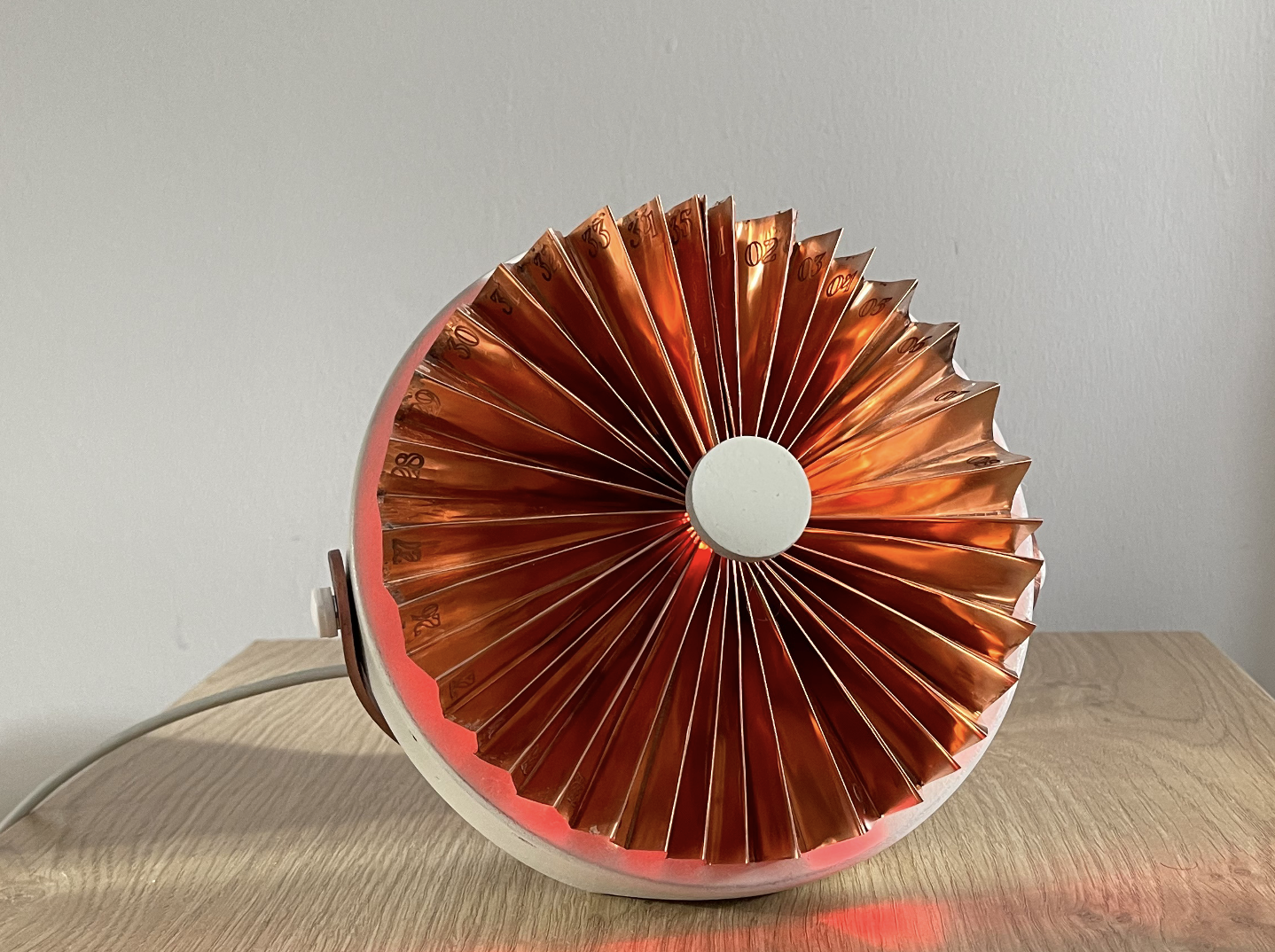 The period. device on a wooden surface, copper fan-shaped calendar glowing red